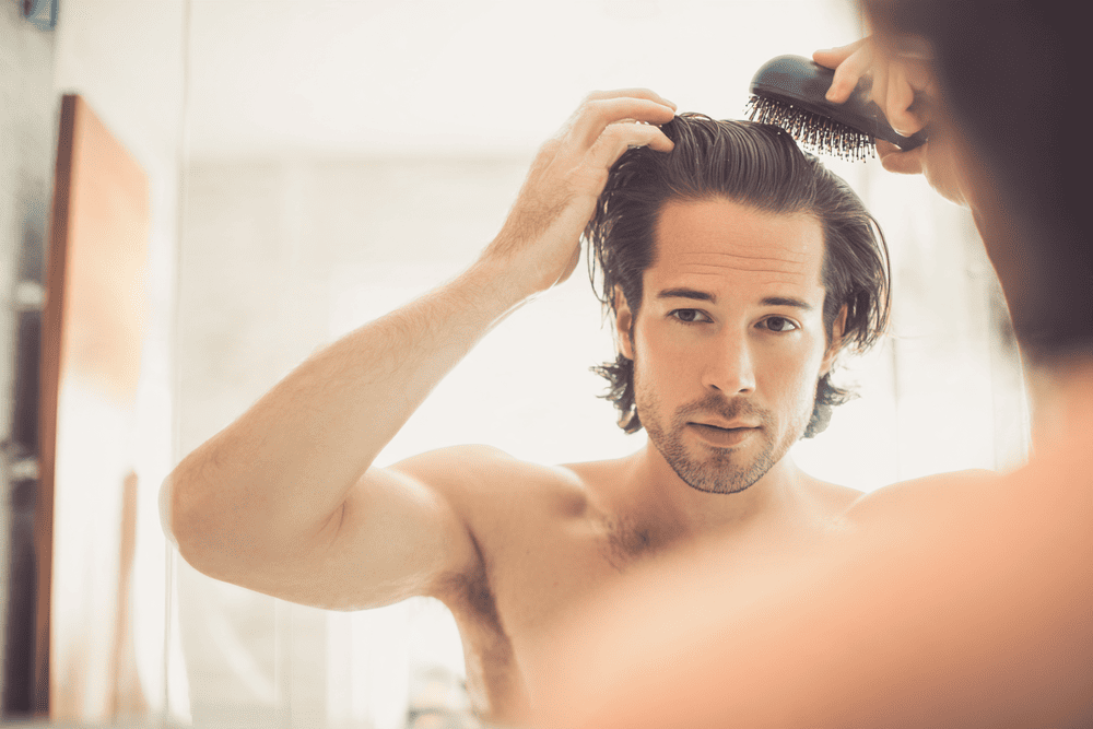 man is zijn haar aan het stylen voor meer volume en textuur